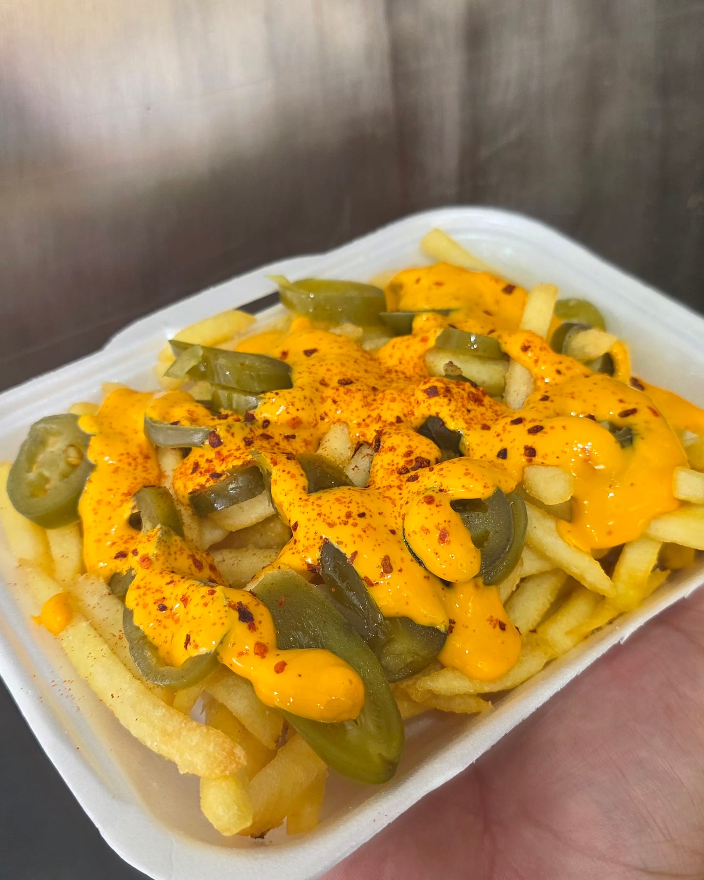 Pommes mit Cheddar-Sauce und Jalapeños in der Box