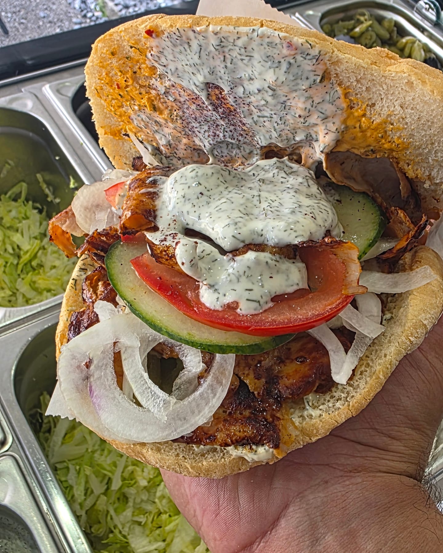Döner mit Tomate, Gurke, Zwiebel und Kräutersoße über der Salattheke